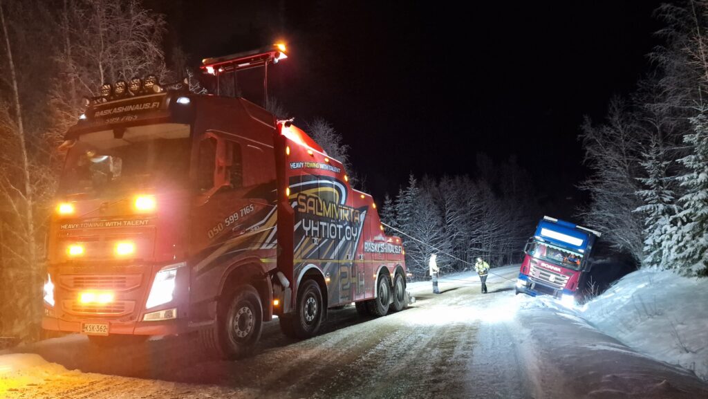 Hinauspalvelu Salmivirran hinausauto vetää rekkaa pois ojasta lumisella tiellä